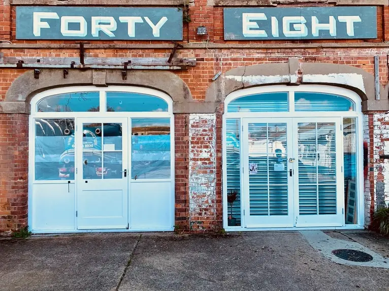 Bespoke large timber arched exterior entryway doorsets custom fabricated for commercial workspace units