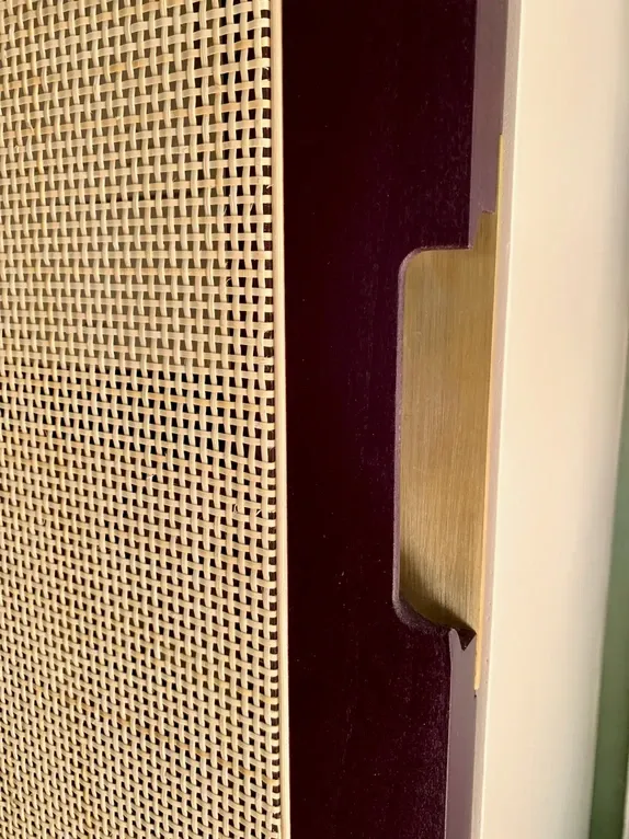 Close-up detail shot of a custom integrated brass fingerpull handle on modern wardrobe cabinetry